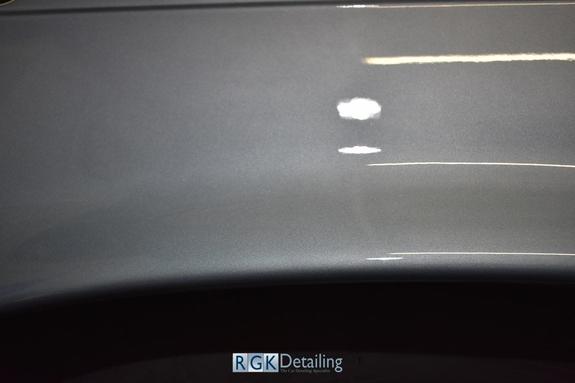 A close up of a gray car with a white spot on it.