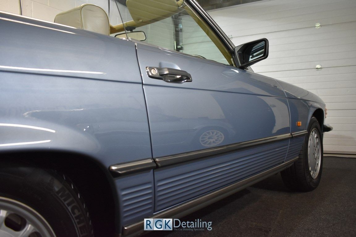 A blue car is parked in front of a garage door.