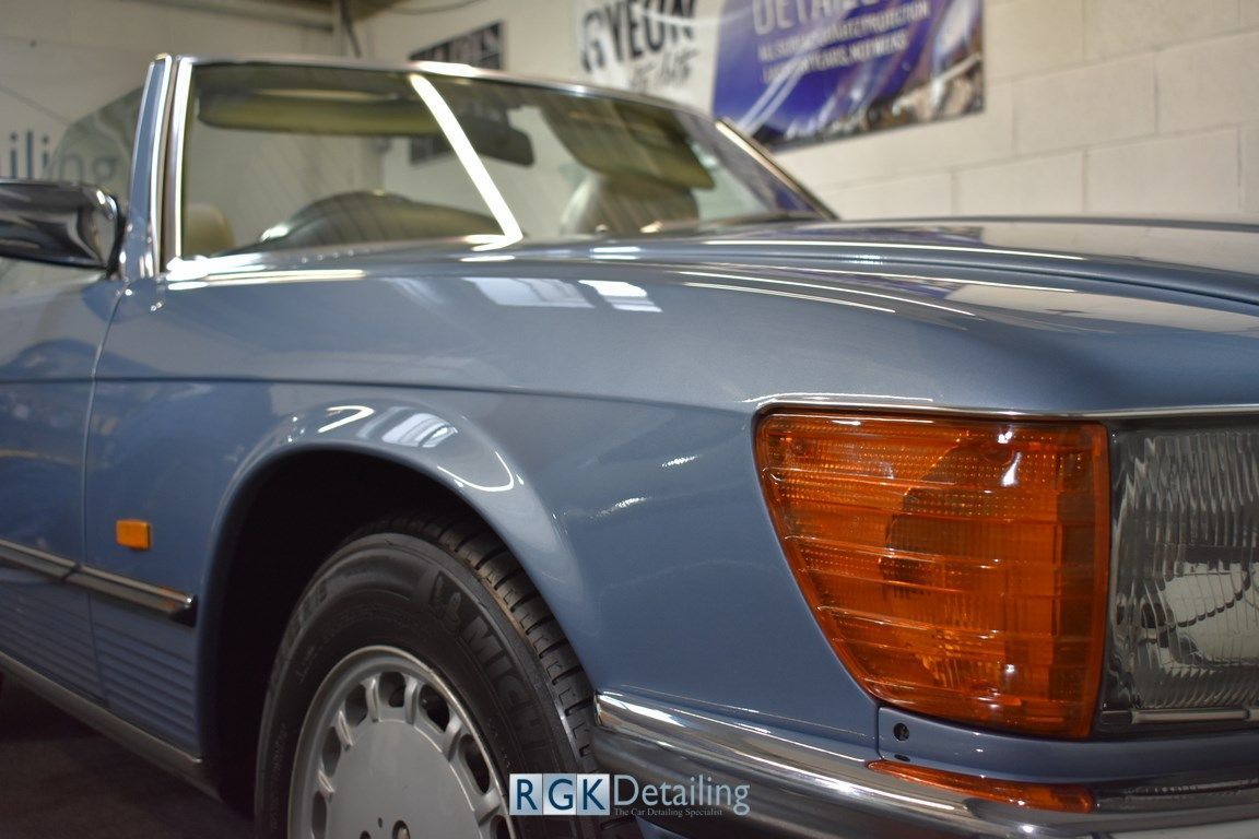 A blue car with a red headlight is parked in a garage.