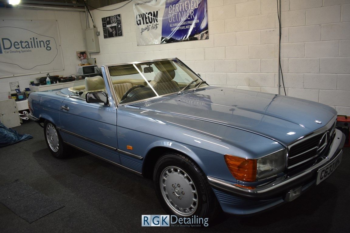 A blue mercedes benz sl500 convertible is parked in a garage.