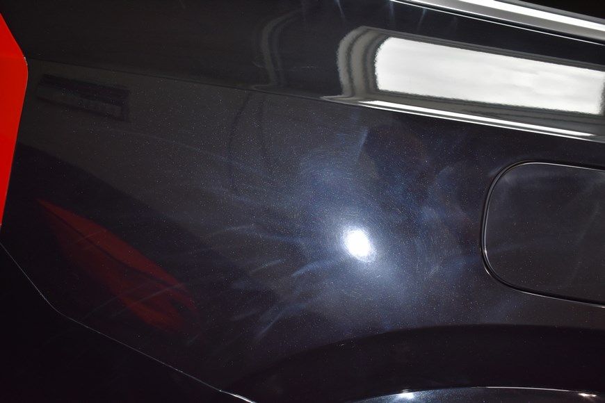 A close up of a black car with a light shining on it.
