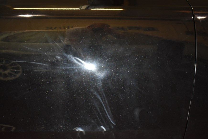 A close up of a car door with a reflection of a person in it.