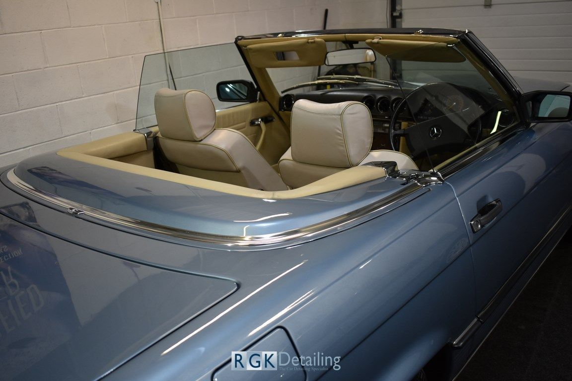 A blue convertible with the top down is parked in a garage.