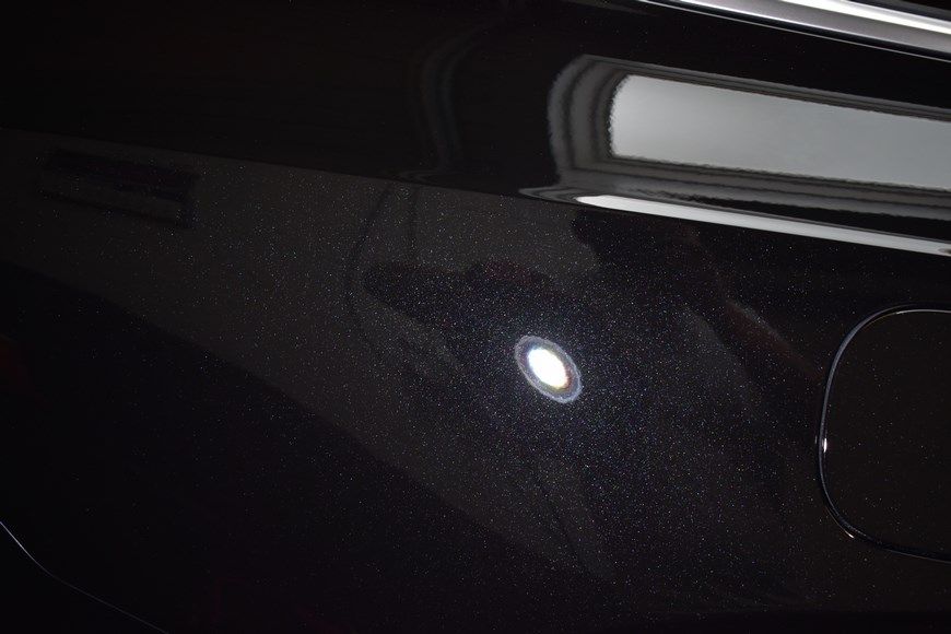 A close up of a black car with a white spot on it.