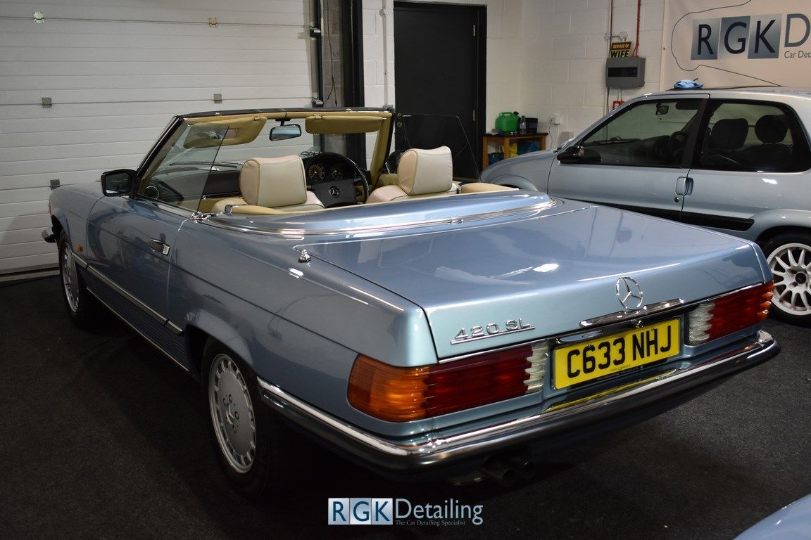 A blue convertible mercedes benz is parked in a garage.
