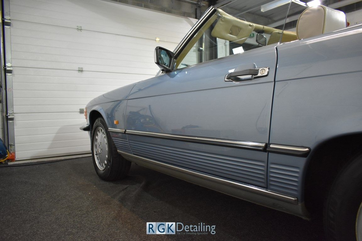 A blue car is parked in front of a garage door.