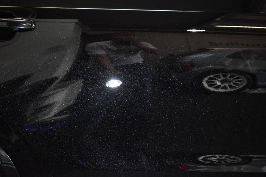 A man is standing in front of a car with a flashlight in his hand.