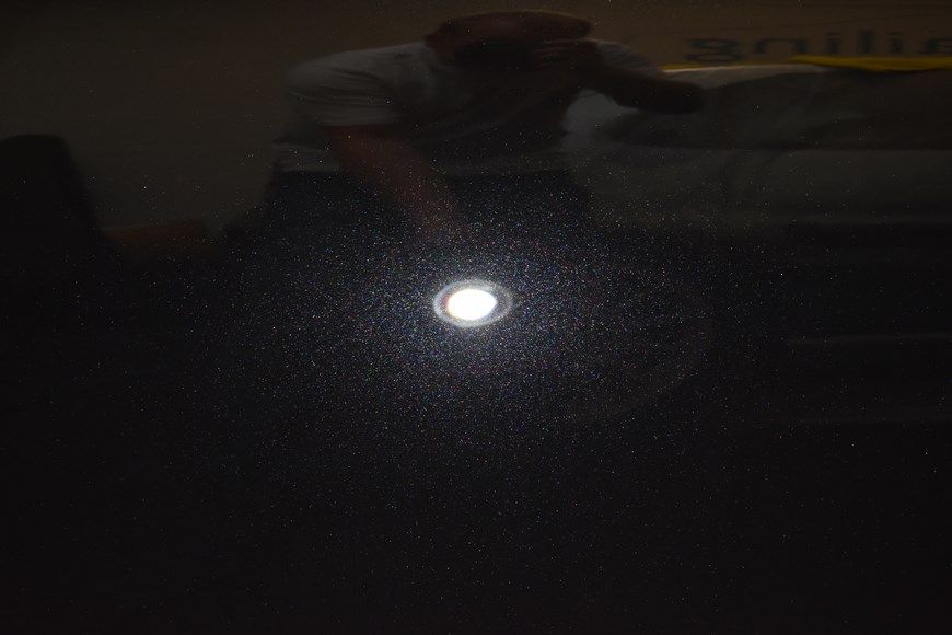A man is holding a flashlight in his hand in the dark.