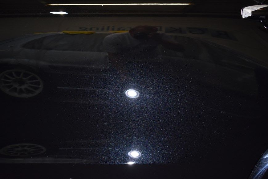 A person is taking a picture of a car in a parking garage.
