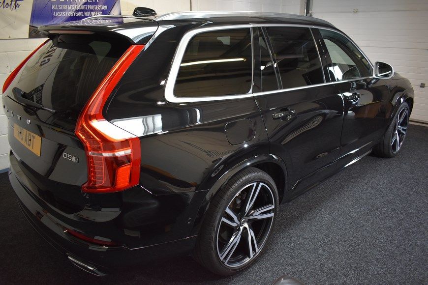 A black volvo xc90 is parked in a garage.