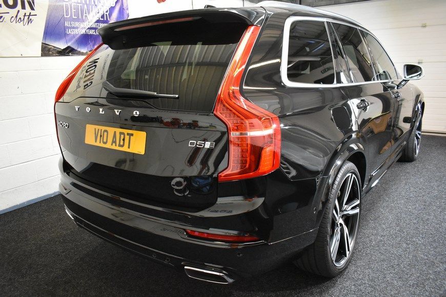A black volvo xc90 is parked in a showroom.