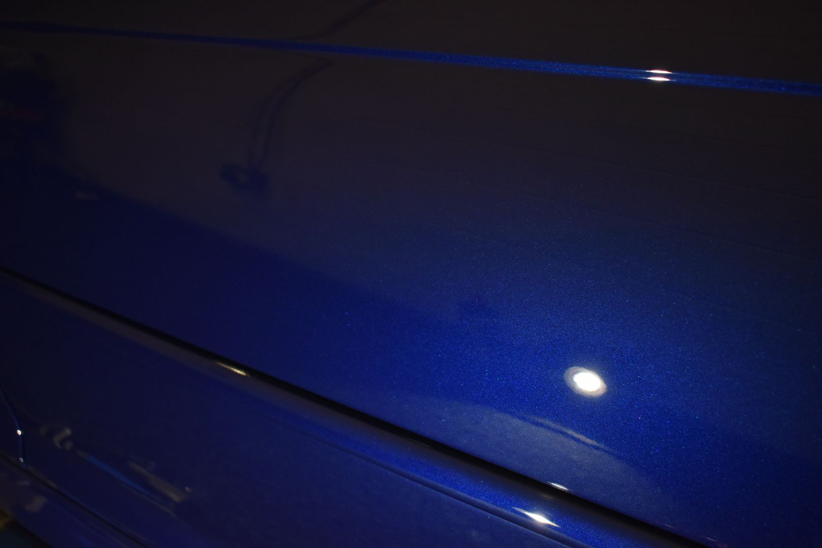 A close up of a blue car with a light shining on it.