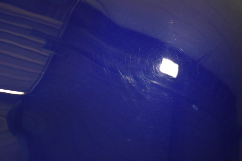A close up of a blue car with a light shining on it.
