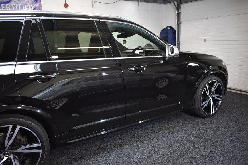 A black car is parked in a garage next to a garage door.