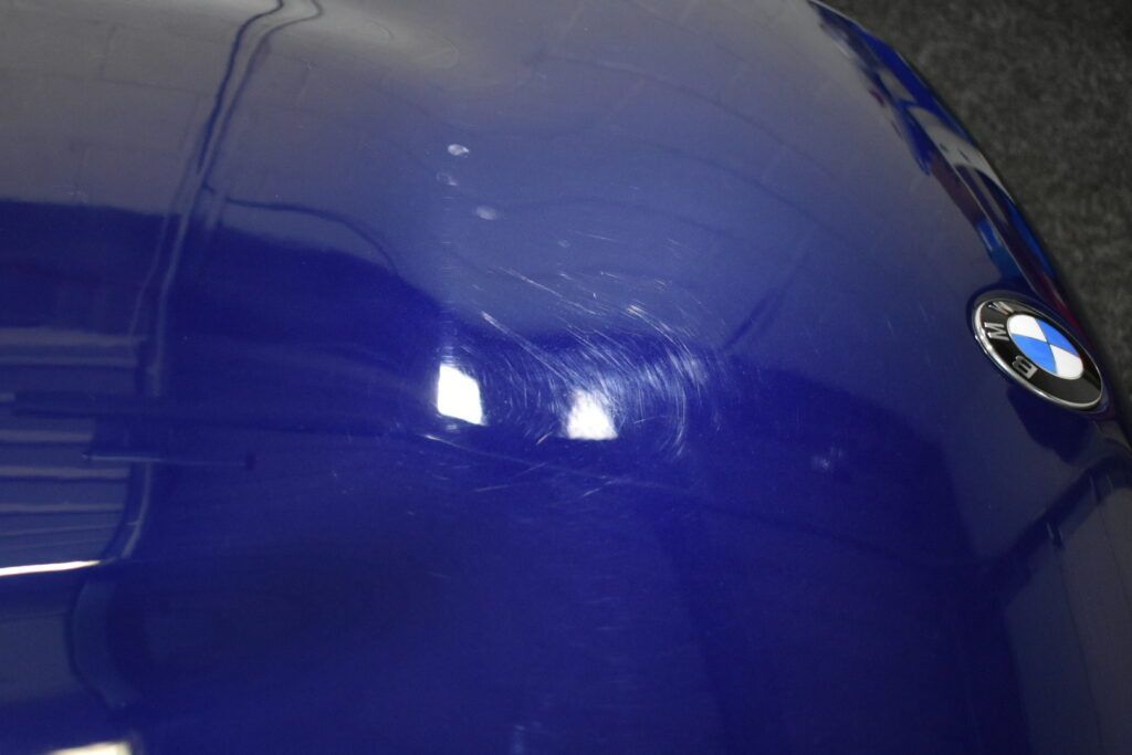 A close up of the hood of a blue bmw car.