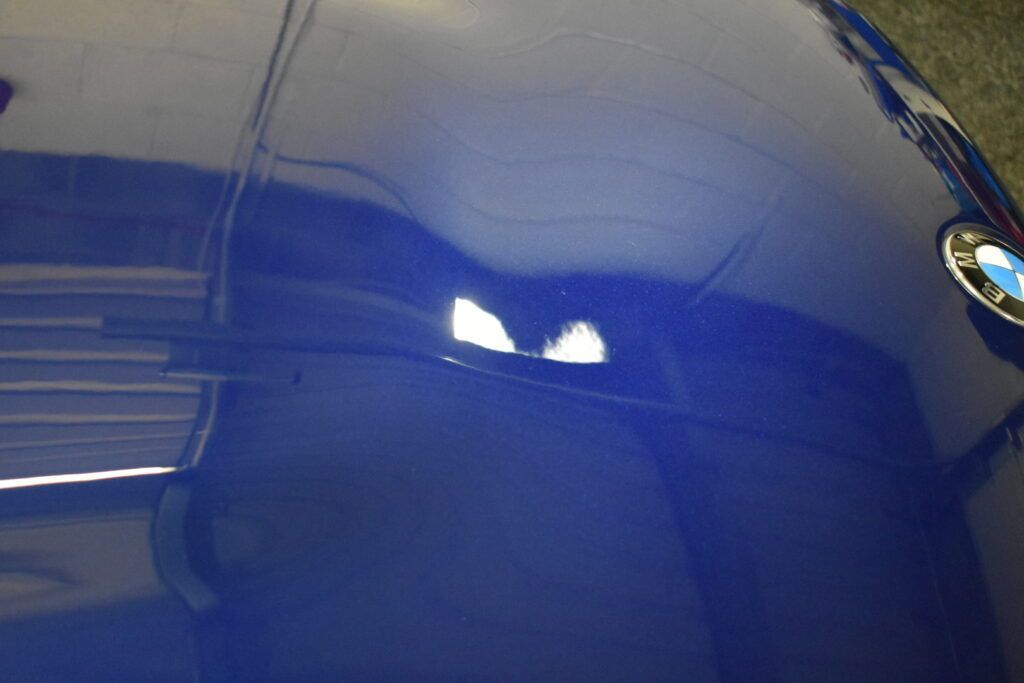 A close up of the hood of a blue bmw