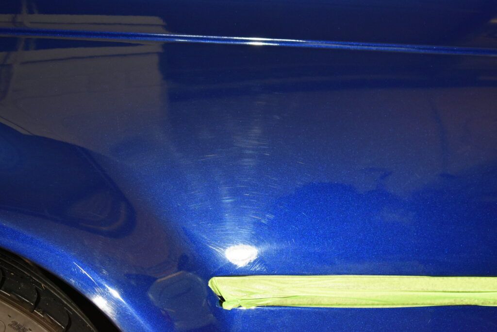 A close up of a blue car with green tape on it.