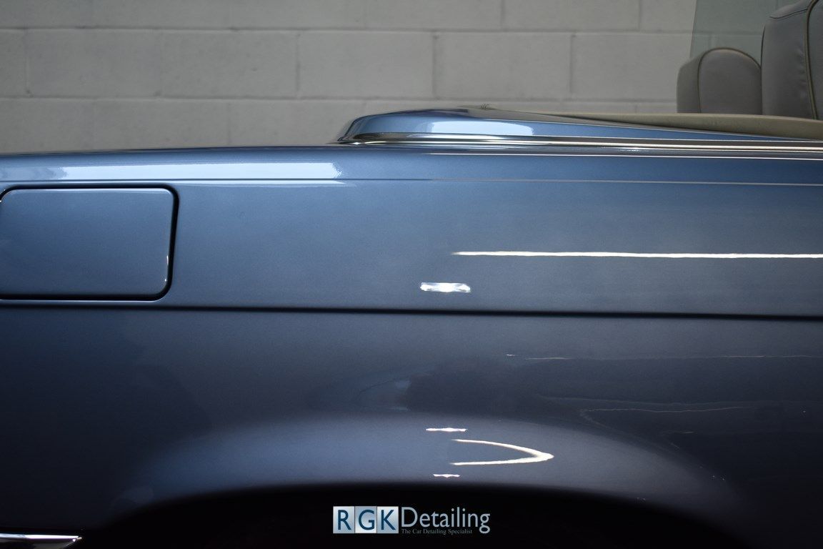 A blue car is parked in a garage with rgk detailing written on the side