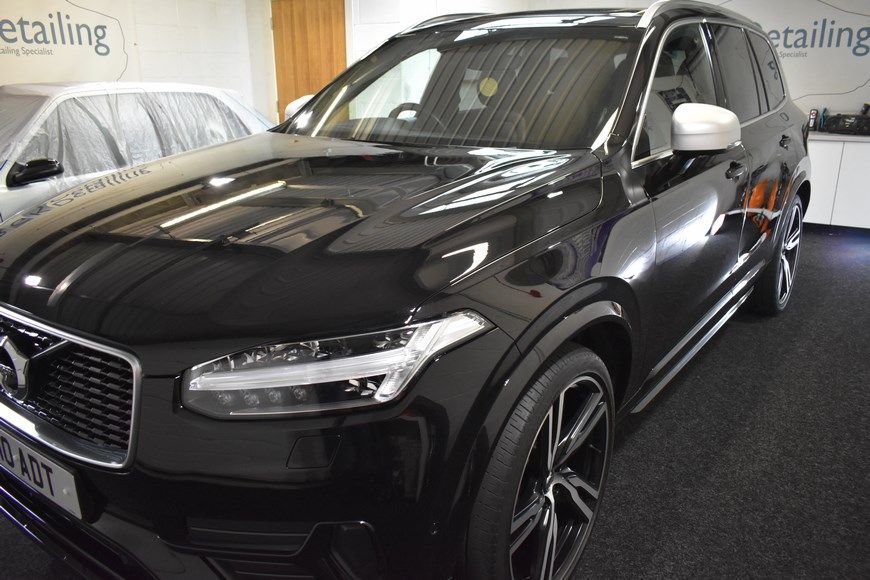 A black volvo xc90 is parked in a garage.