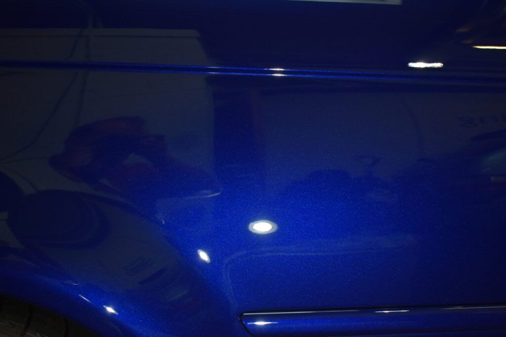 A blue car is parked in a dark room