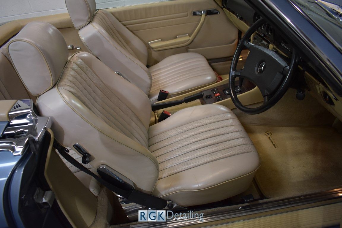The interior of a blue mercedes with tan seats and a steering wheel