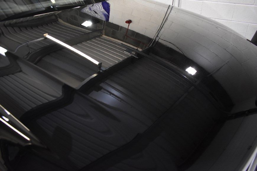 The hood of a black car is reflected in the windshield