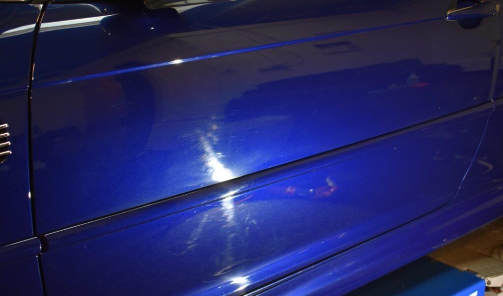 A blue car is parked on a lift in a garage.