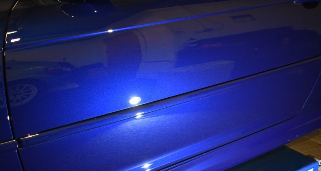 A close up of a blue car door in a garage.