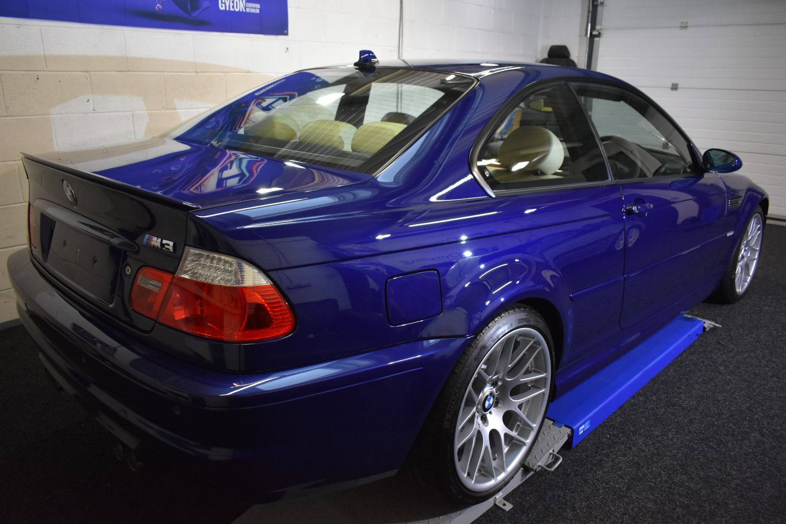 A blue bmw m3 is sitting on a lift in a garage.