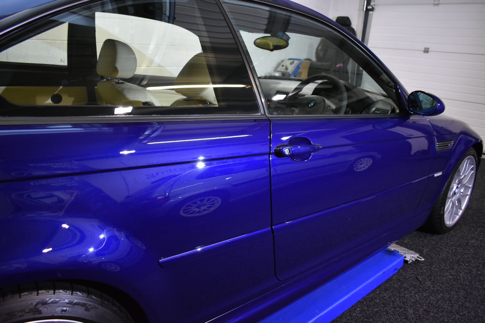 A blue car is parked in front of a garage door
