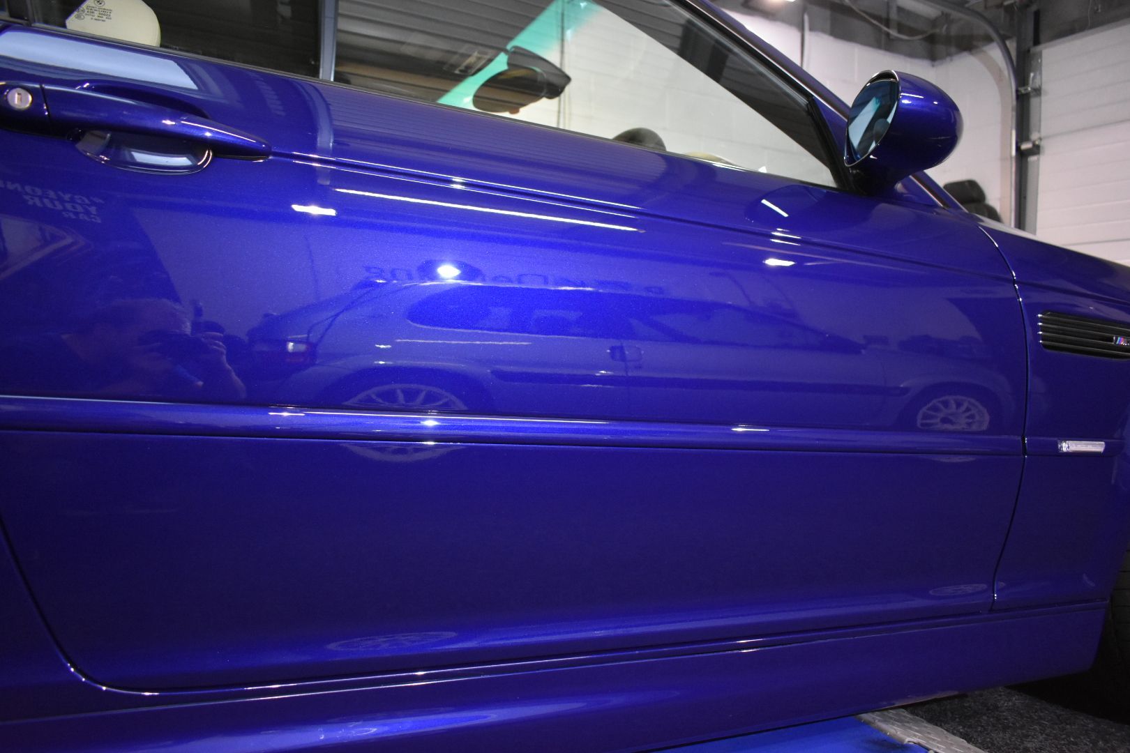 A blue car is parked in a garage with the door open
