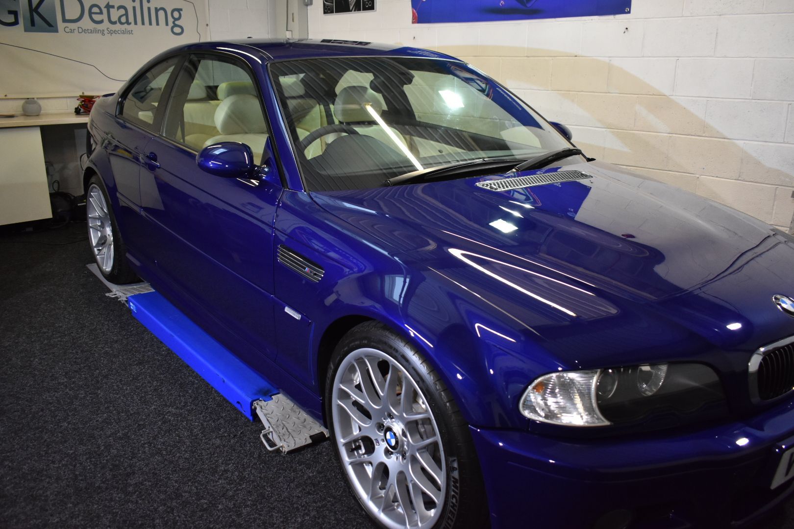A blue bmw is sitting on a lift in a garage.