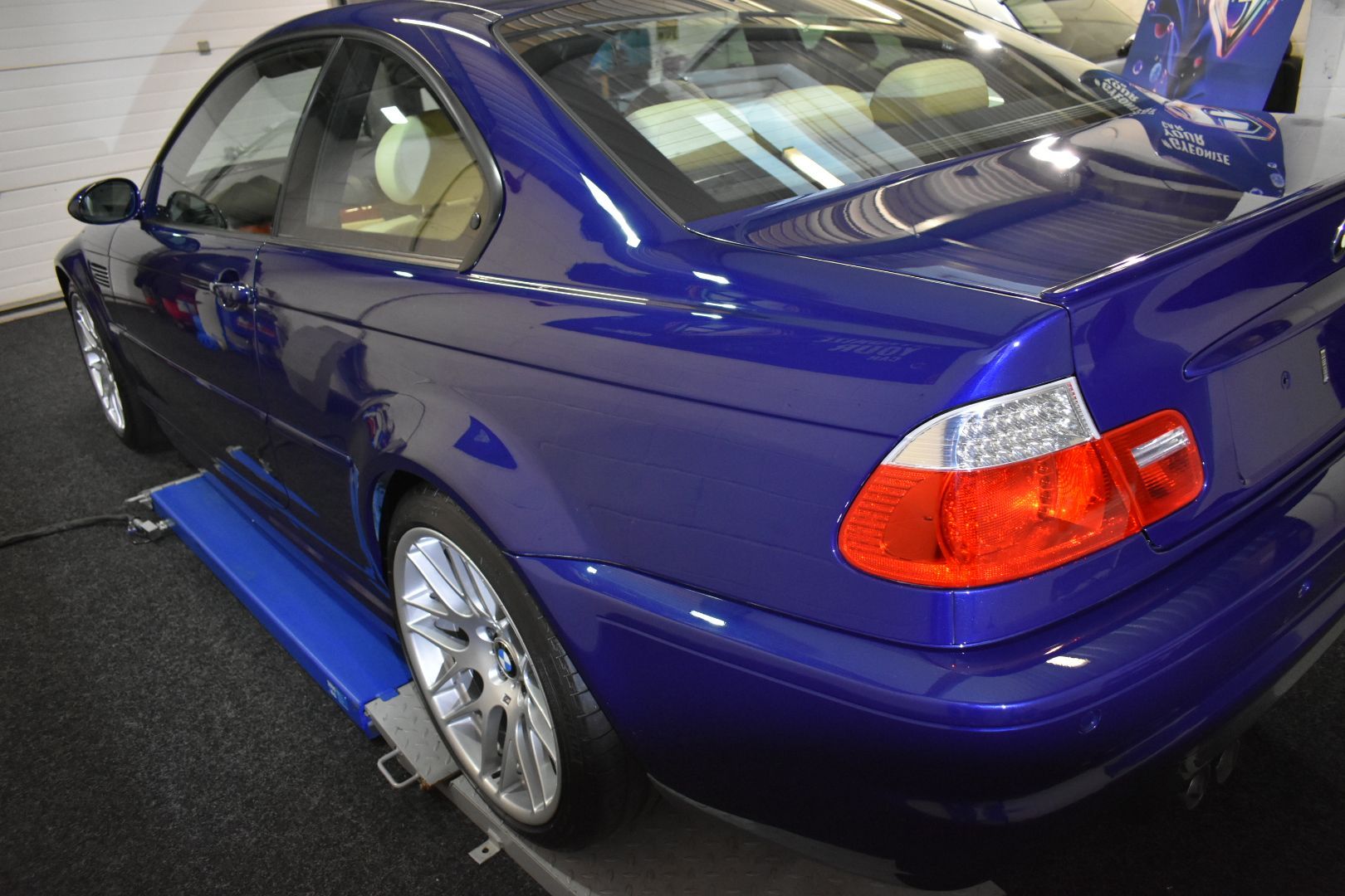 A blue bmw is parked on a lift in a garage