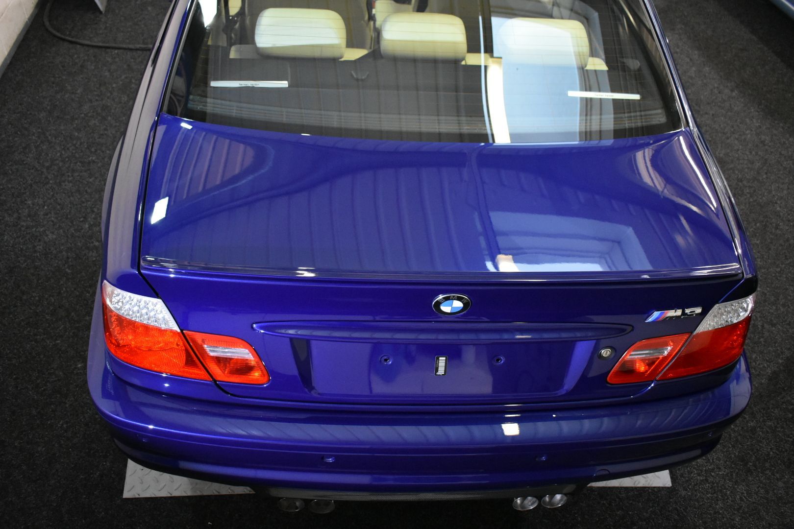 The rear end of a blue bmw is shown from above