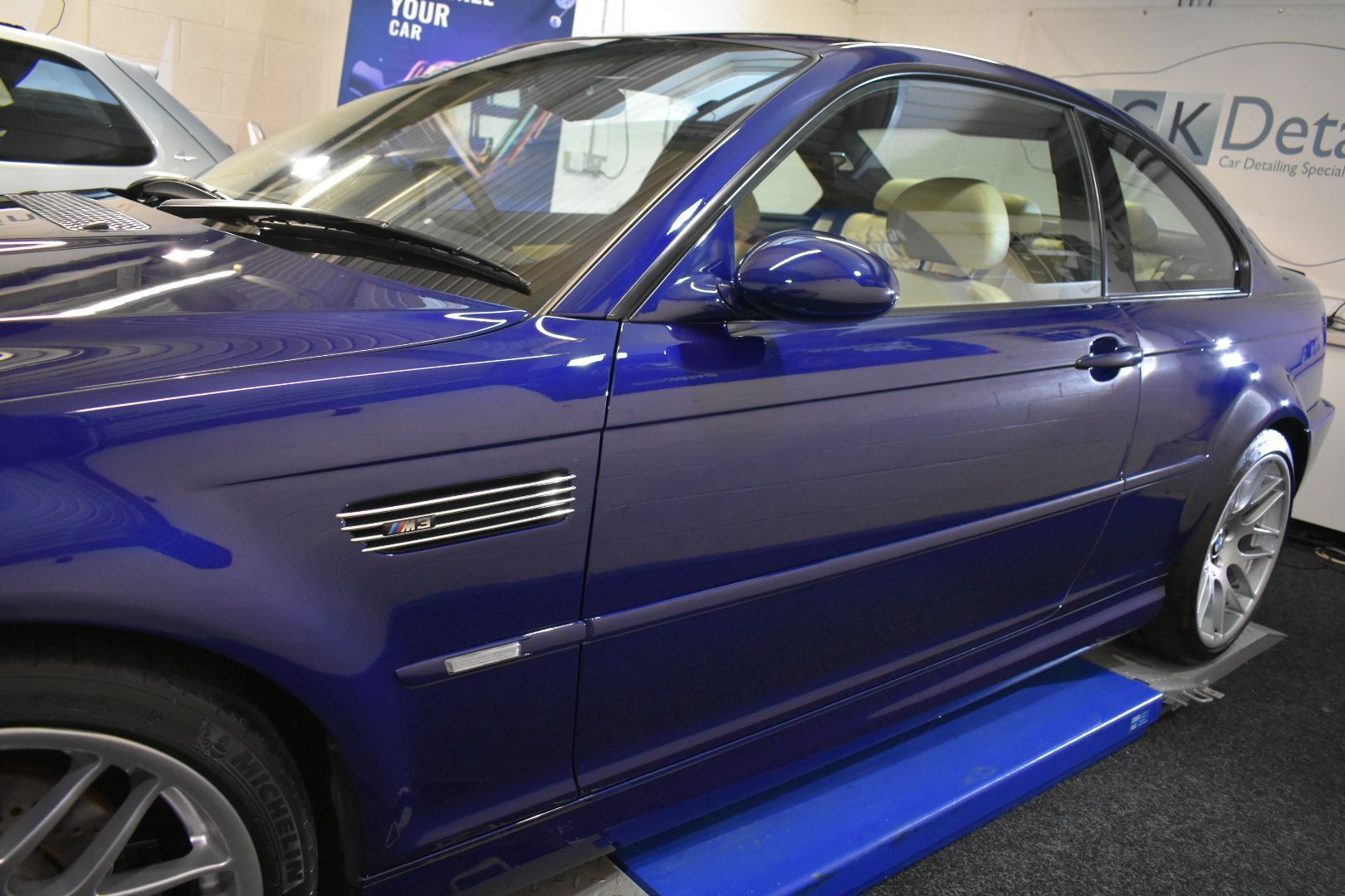 A blue car is sitting on a lift in a garage.