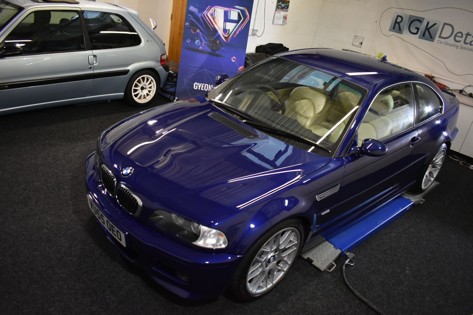 A blue bmw is sitting on a lift in a garage.