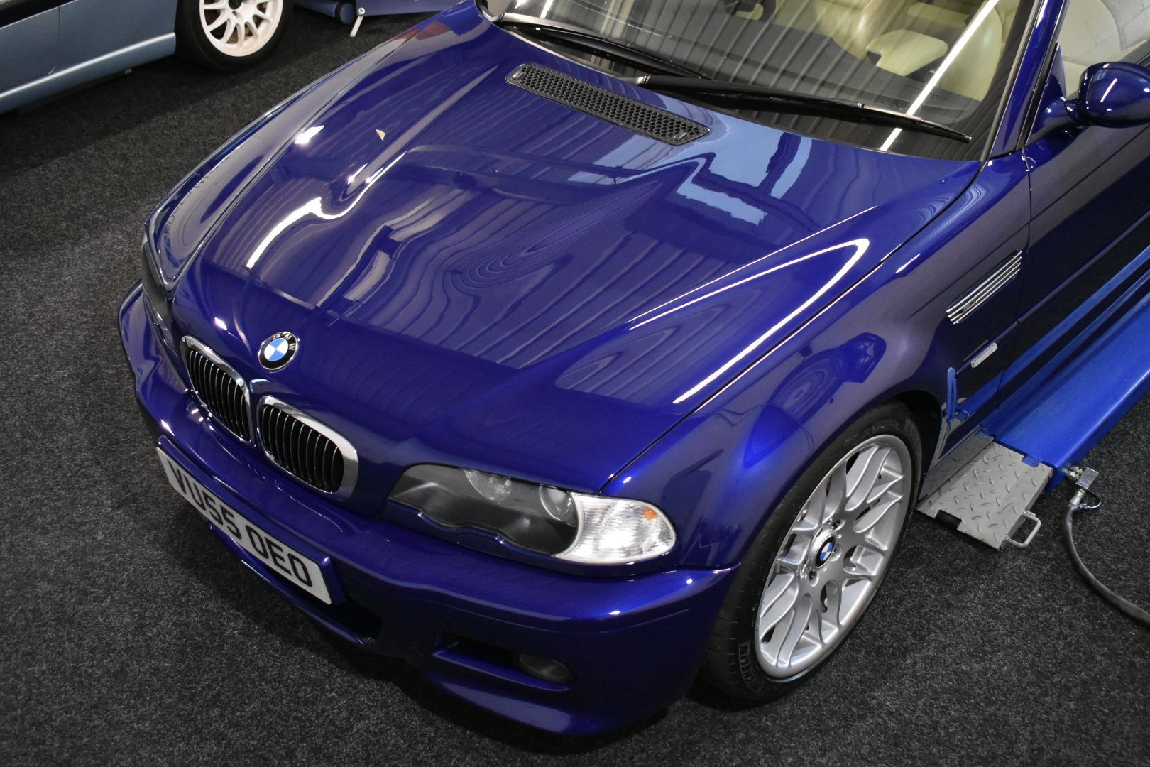 A blue bmw is sitting on a lift in a garage