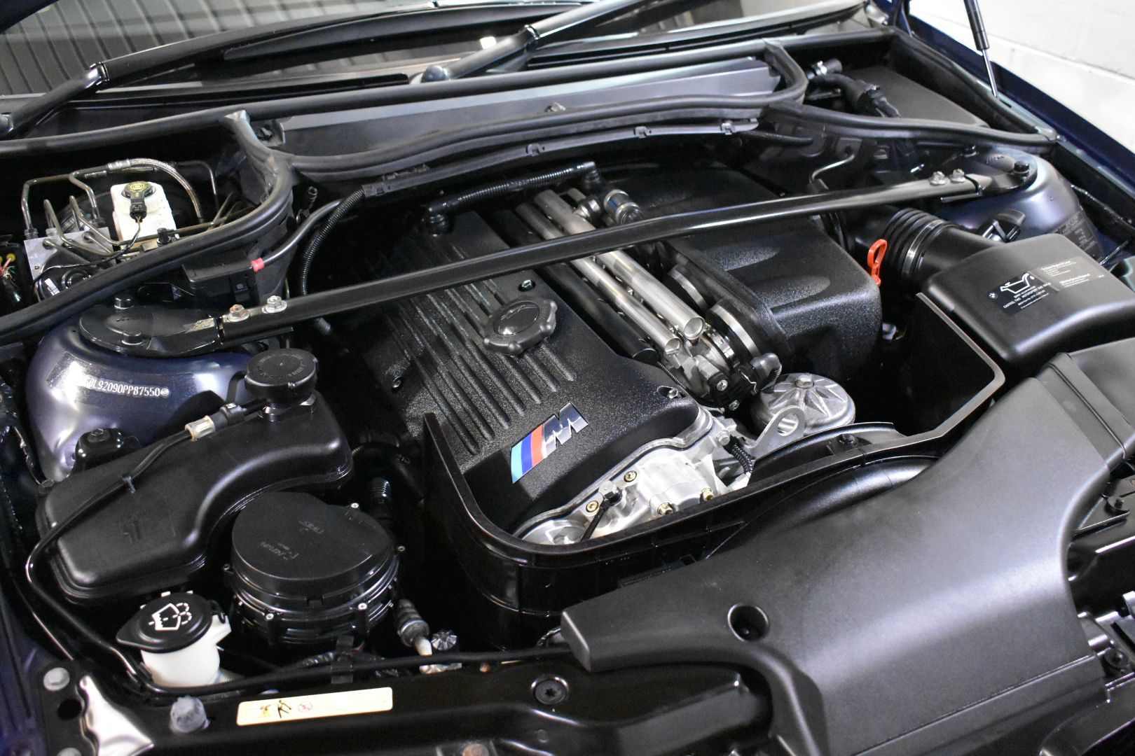A close up of the engine of a car with the hood open.
