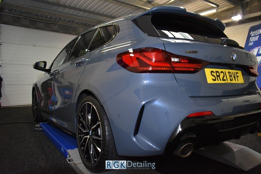 A blue bmw is sitting on a lift in a garage.