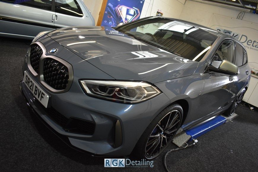 A grey bmw is sitting on a lift in a garage.