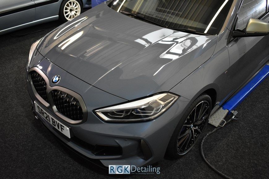 A gray bmw is sitting on a lift in a garage.