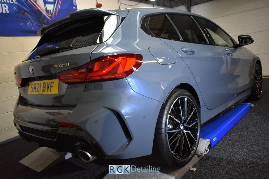 A bmw 1 series is sitting on a lift in a garage.