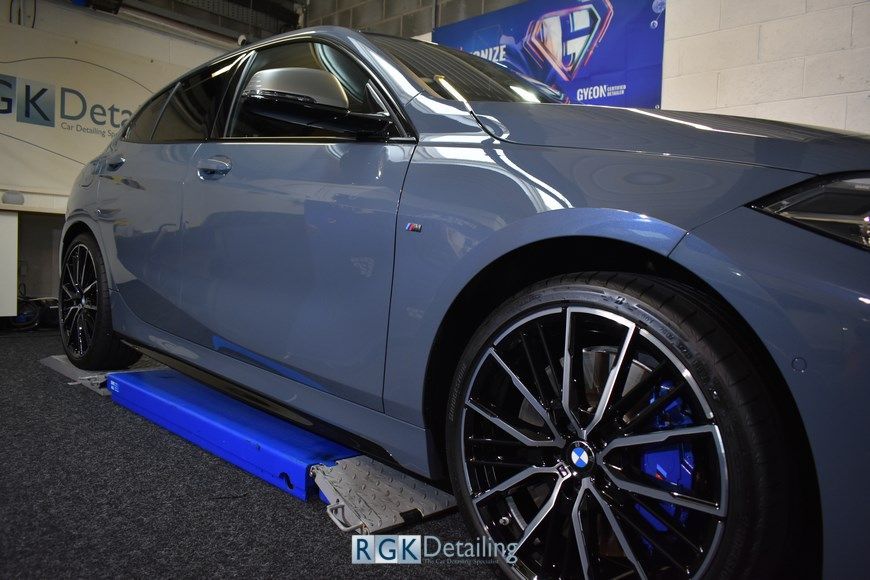 A blue bmw is sitting on a lift in a garage.