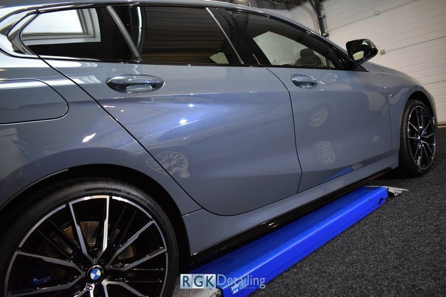 A bmw is sitting on a blue platform in a garage.