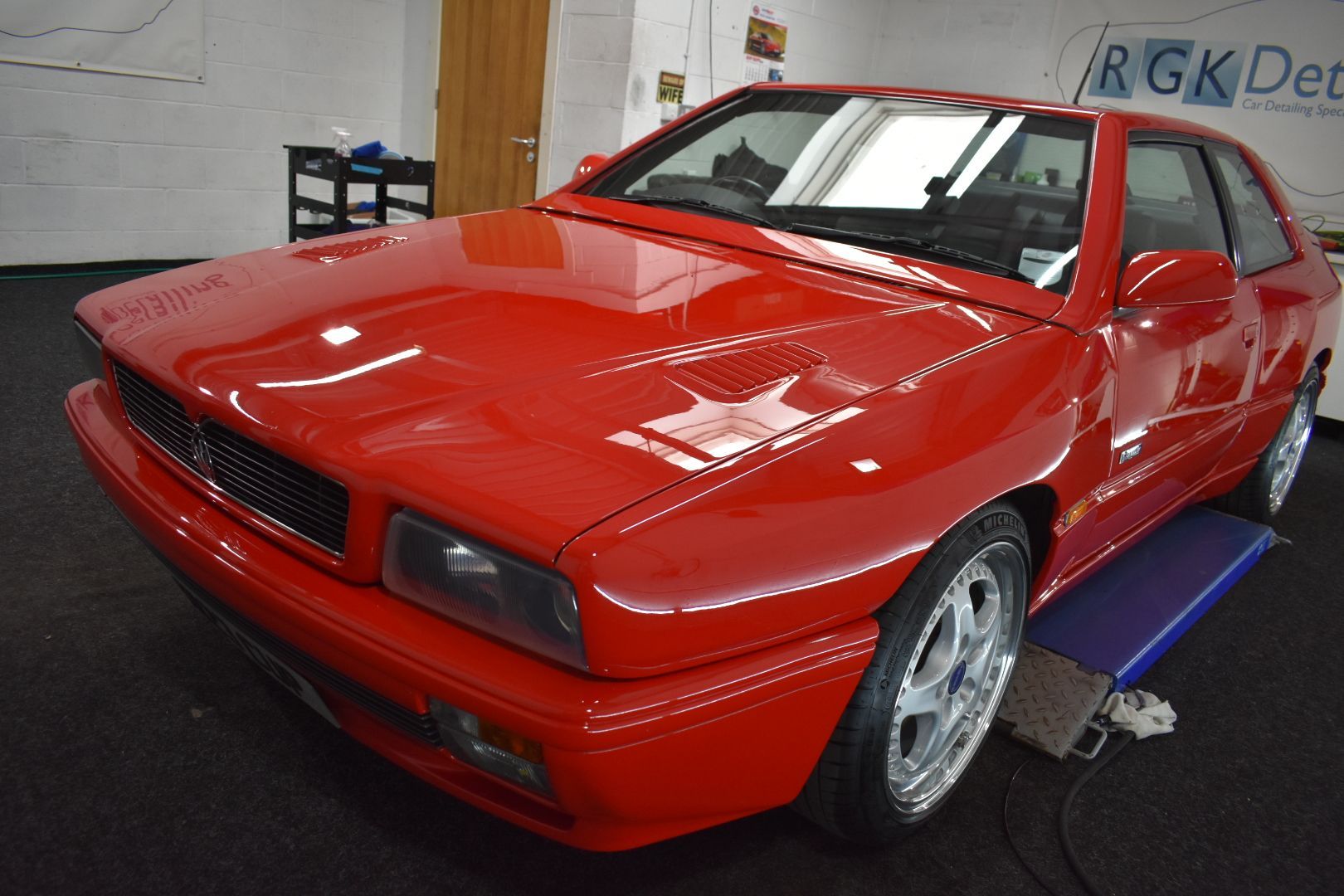 A red car is sitting on a lift in a garage