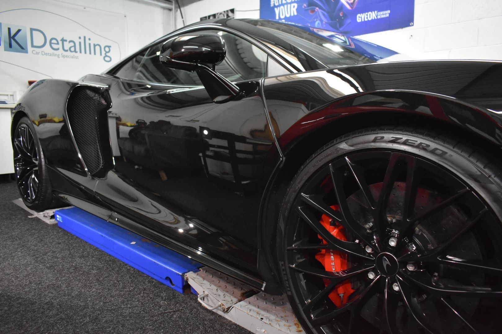 A black sports car is sitting on top of a blue lift.