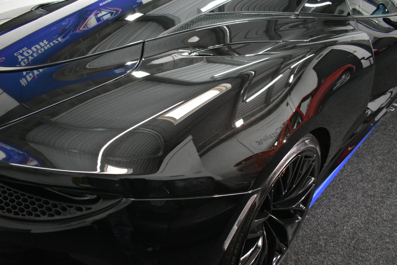 A close up of a black car with a reflection of another car