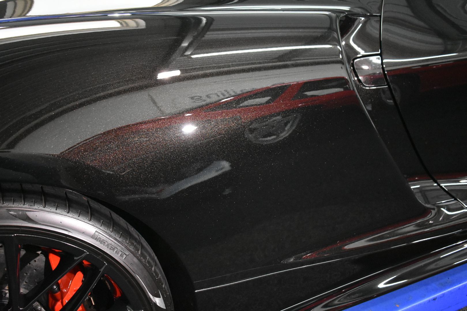 A close up of a black car with red brake calipers