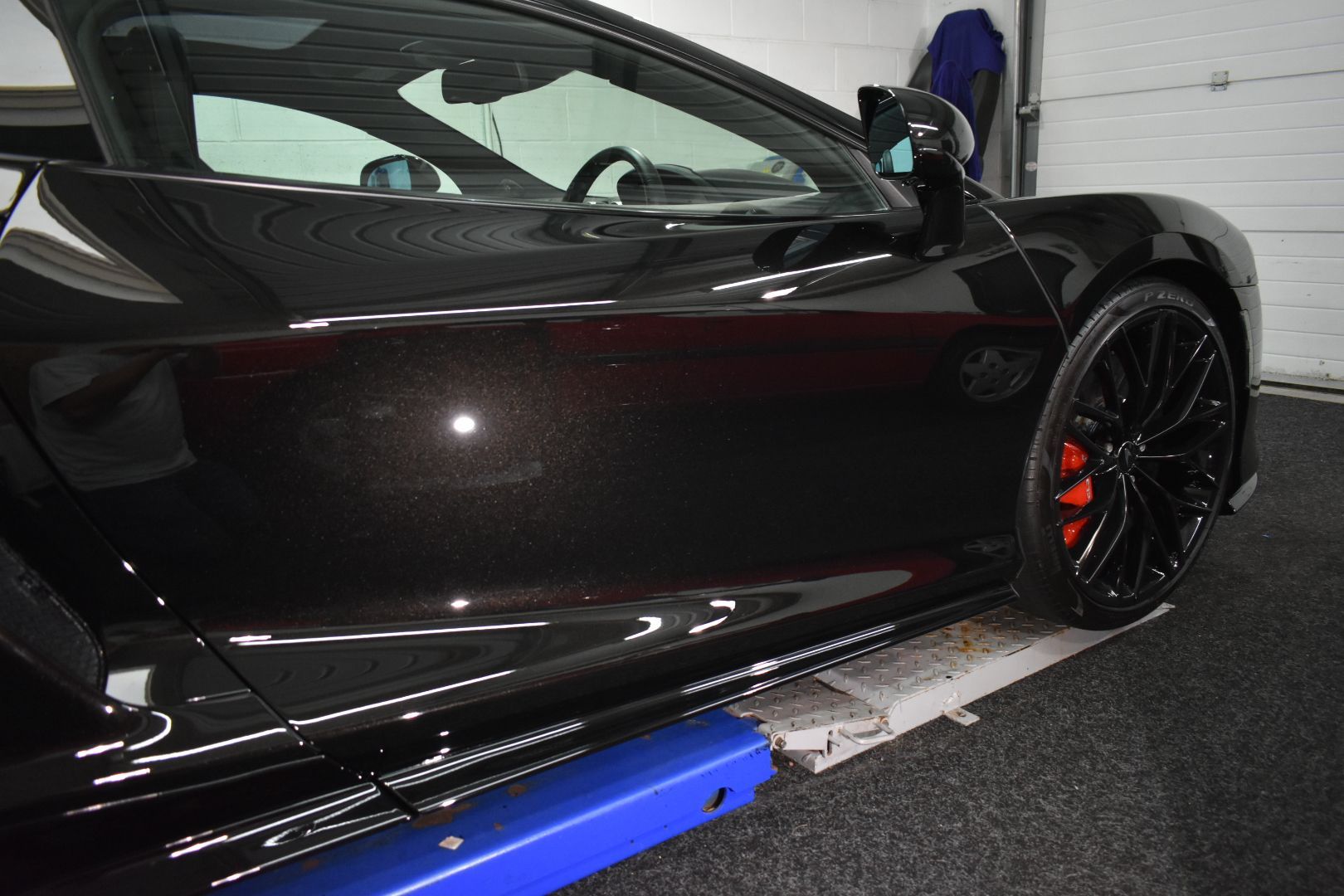 A black sports car is sitting on a lift in a garage.