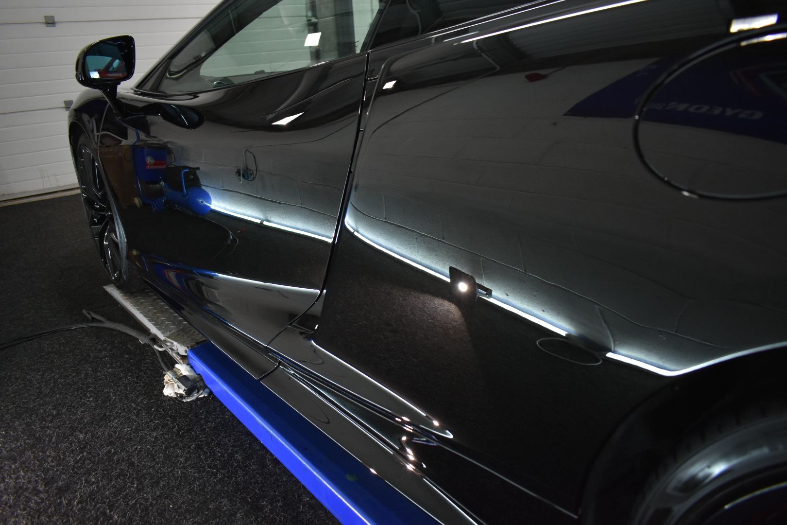 A black sports car is parked in a garage.